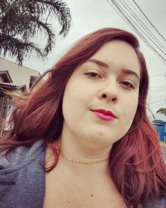 Mulher ruiva com um singelo sorriso em seu rosto.