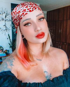 Mulher loira em uma selfie, com bandana na cabeça.