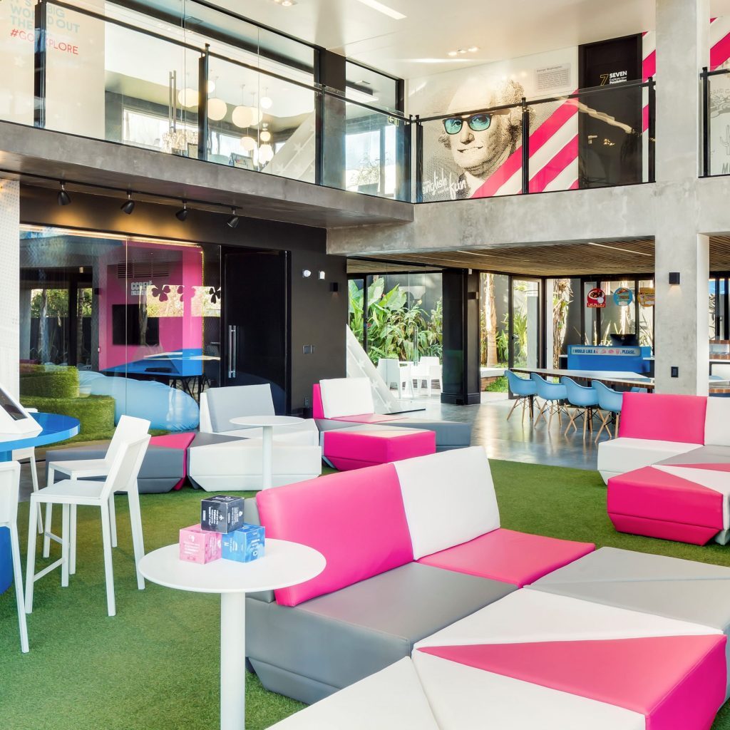 Espaço com sofás rosa e branco em formato triangular.